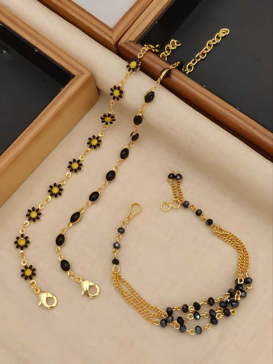 Gold bracelets with black and yellow beads on a beige surface